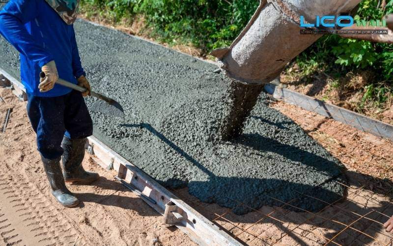 Ống dẫn đang đưa bê tông tươi xuống và công nhân làm phẳng bề mặt phía dưới